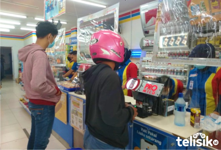 Pengunjung kios/mini market menggunakan masker dan penutup kepala (helm). Foto: Fitrah Nugraha/Telisik