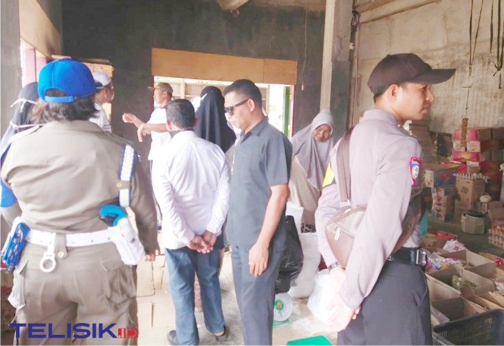 KUPTD Pasar, Jumaddin bersama Plt Kades Lanosandana, Burhanuddin, membubarkan kerumunan warga di pasar. Foto: Naryo/Telisik
