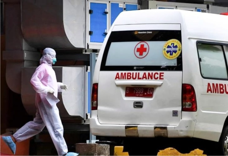 Seorang petugas kesehatan mengarah ke mobil ambulance. Foto: Repro Reuters