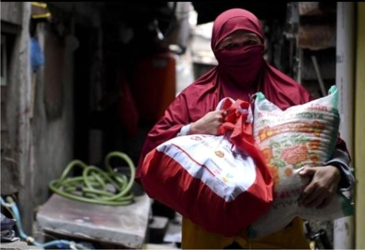 Warga yang membawa paket Bantuan Sosial. Foto: Antara