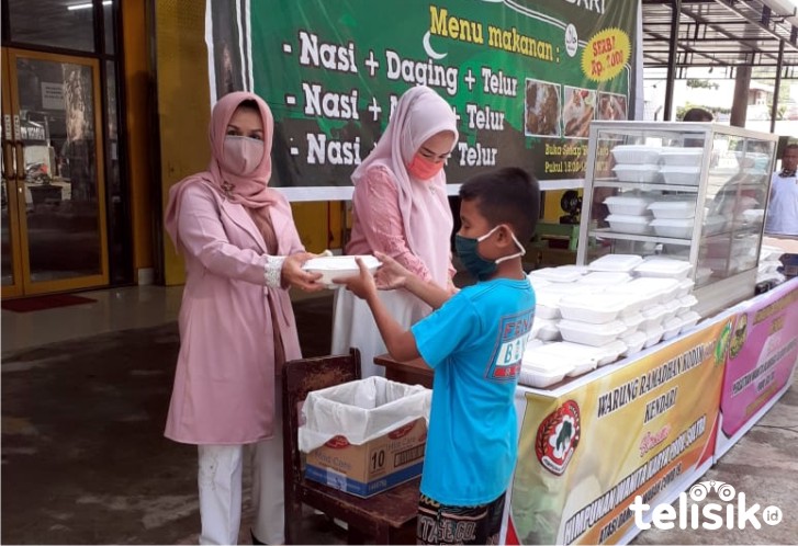 Ketua Perwosi Sultra, Dewi Tamburaka, sedang memberikan nasi ke pembeli di Warung Kodim 1417 Kota Kendari. Foto: Ist.