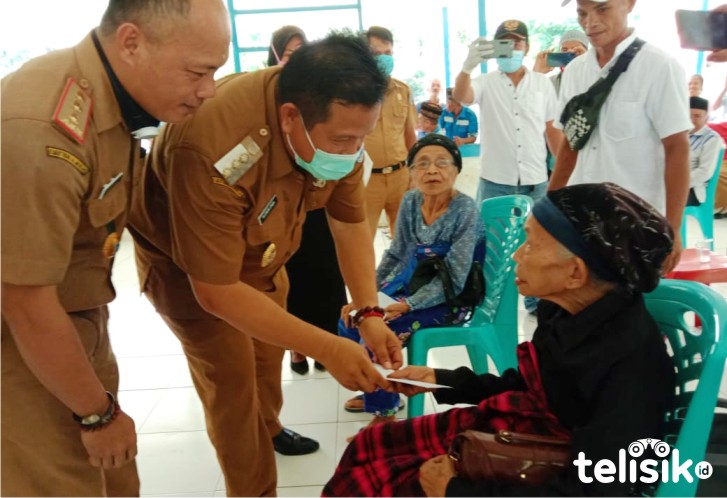 Kadis PMD Muna, Rustam, mendampingi Bupati Muna menyalurkan BLT. Foto: Naryo/Telisik
