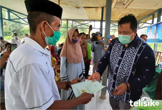 Bupati Muna, LM Rusman Emba menyerahkan sertifikat lahan pada warga trans. Foto: Sunaryo/Telisik