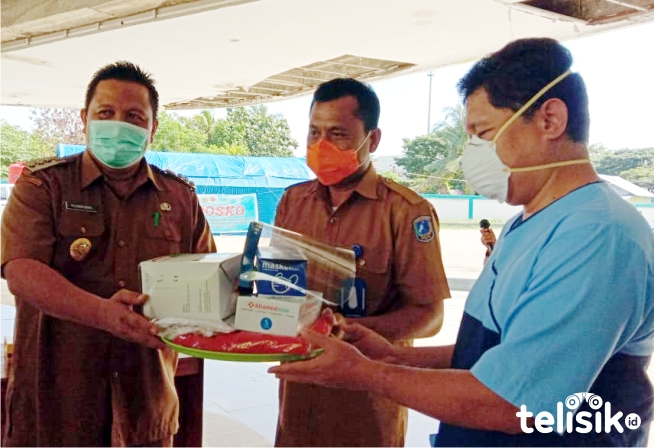 Jubir Satgas COVID-19 Muna, dr La Ode Ahmad Wahid Agigi menerima APD dari Bupati, LM Rusman Emba. Foto: Sunaryo/Telisik