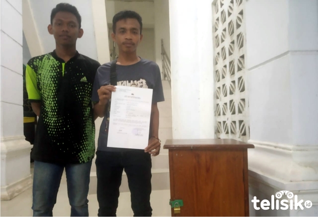 Dua remaja masjid memperlihatkan bukti laporan polisi dan kotak amal yang dibobol maling. Foto: Sunaryo/Telisik