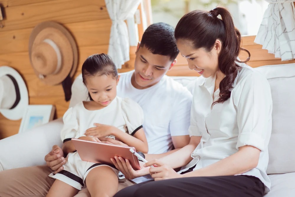 Ilustrasi ibu dan bapak mendampingi anak bermain gawai. Foto: Shutterstock