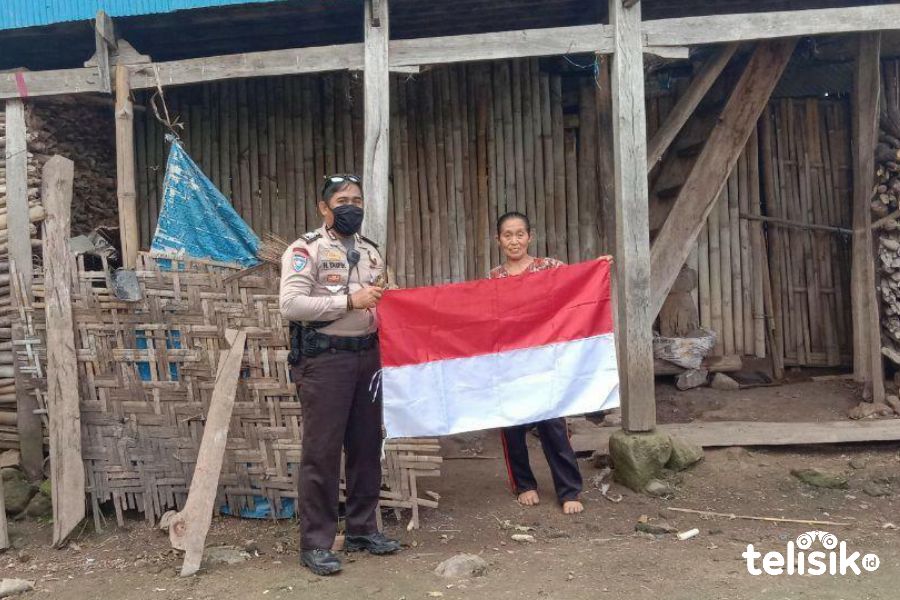 Bhabinkamtibmas Brigadir Taufik, membagikan bendera merah putih kepada warga kurang mampu di desa binaannya, Dusun Parang Labbua, Desa Kayu Loe, Kecamatan Bantaeng, Kabupaten Bantaeng, Sulawesi Selatan. Foto: Rezki Mas'ud/Telisik