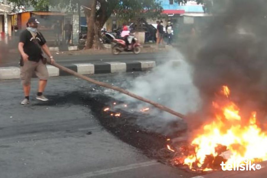 Nampak seorang pria yang membersihkan sisa ban terbakar pendemo. Foto: Rezki Mas'ud/Telisik