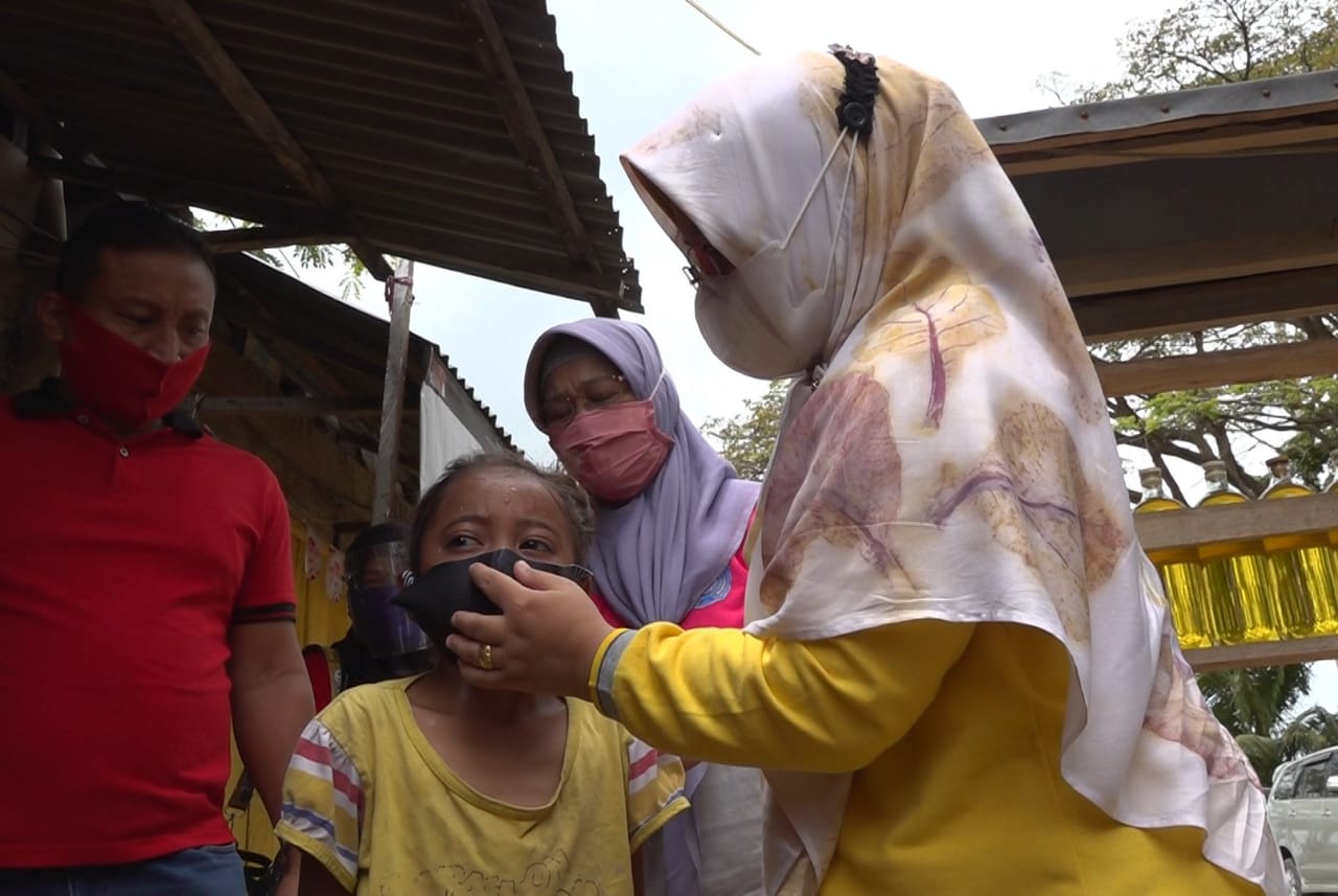 Ketua Tim Penggerak PKK Kota Kendari, Sri Lestari Sulkarnain memasangkan masker pada seorang anak. Foto: Ist.