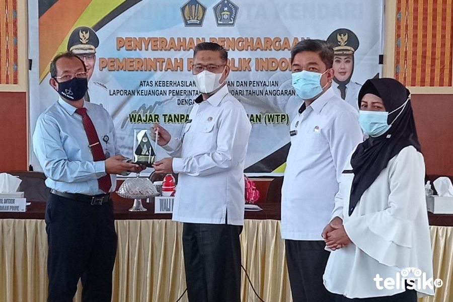 Kakanwil Ditjen Perbendaharaan Negara, Arif Wibawa, menyerahkan plakat penghargaan WTP enam tahun berturut-turut pada Wali Kota Kendari. Foto: Sumarlin/Telisik