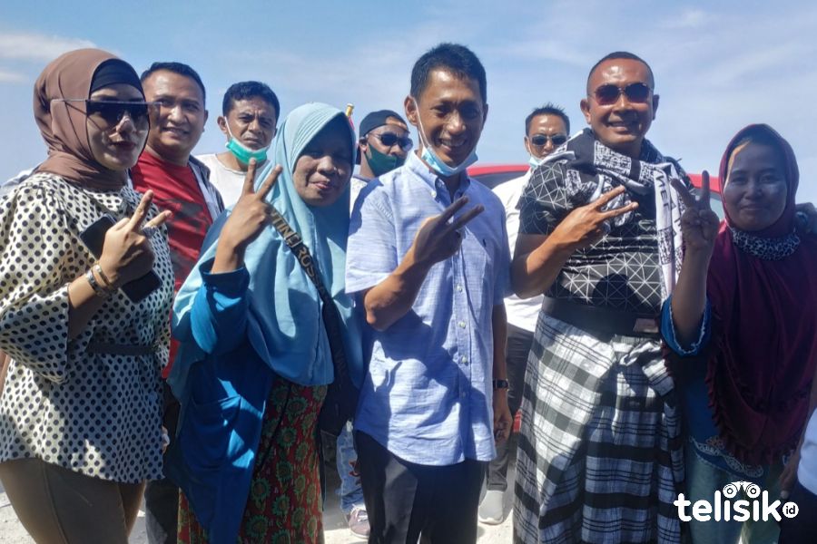Samsu Umar Abdul Samiun (mengenakan sarung) dan Calon Bupati Wakatobi nomor urut dua saat berpose dengan pedagang kaki lima di Pelabuhan Numana, Wangi-wangi. Foto: Deni Djohan/Telisik
