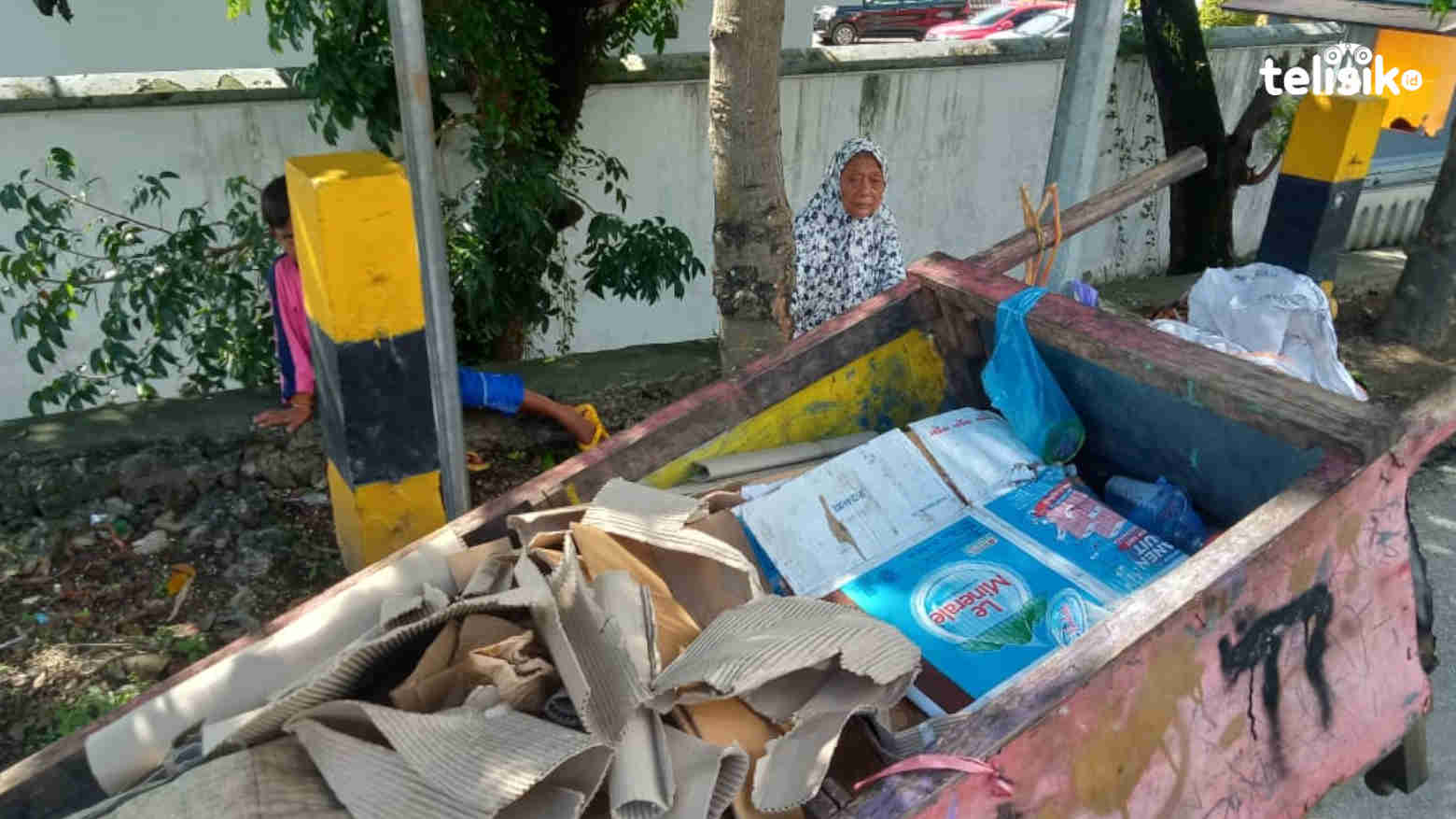 Ibu Naima yang sedang istirahat di tengah usahanya mengumpulkan kardus bekas. Foto: Harjum Ntry/Telisik