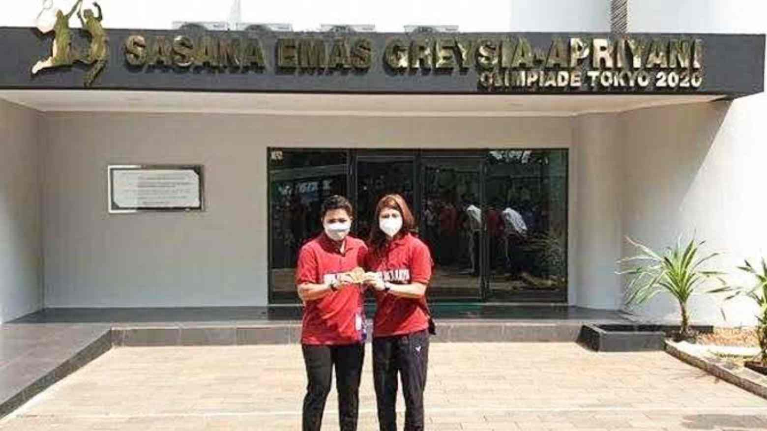 Pebulutangkis ganda putri peraih emas pada Olimpiade Tokyo 2022, Greysia Polii (kanan) dan Apriyani Rahayu (kiri), berpose di depan Sasana Emas Greysia-Apriyani di GOR Ragunan, Jakarta Timur. Foto: Kompas.com