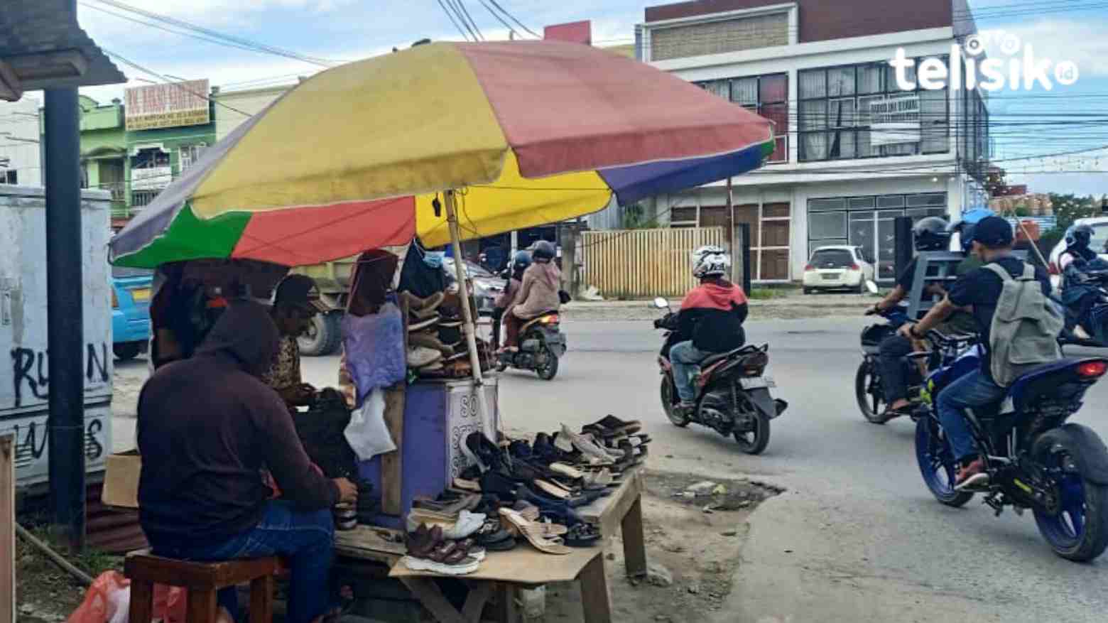 Seorang tukang jahit sepatu di pinggir jalan yang sedang melayani pelanggan. Foto: Umratul Khazanah/Telisik