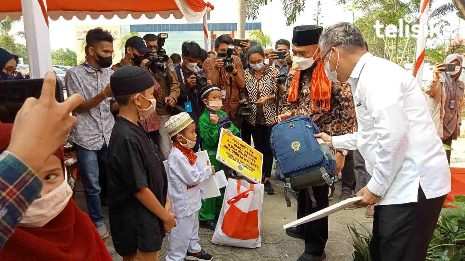 Menko PMK RI, Muhadjir Effendy, didampingi Wali Kota Kendari, Sulkarnain Kadir, memberikan paket bantuan dalam bentuk jaminan pendidikan, uang tunai dan sembako. Foto: Andi Irna Fitriani/Telisik