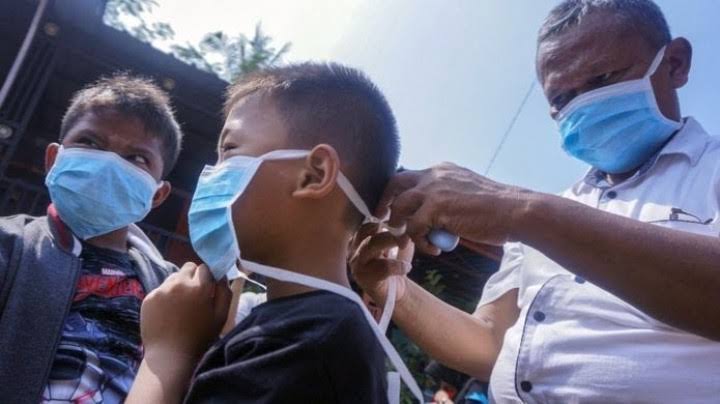 Warga saling memakaikan masker. Foto: Repro suarakarya.id