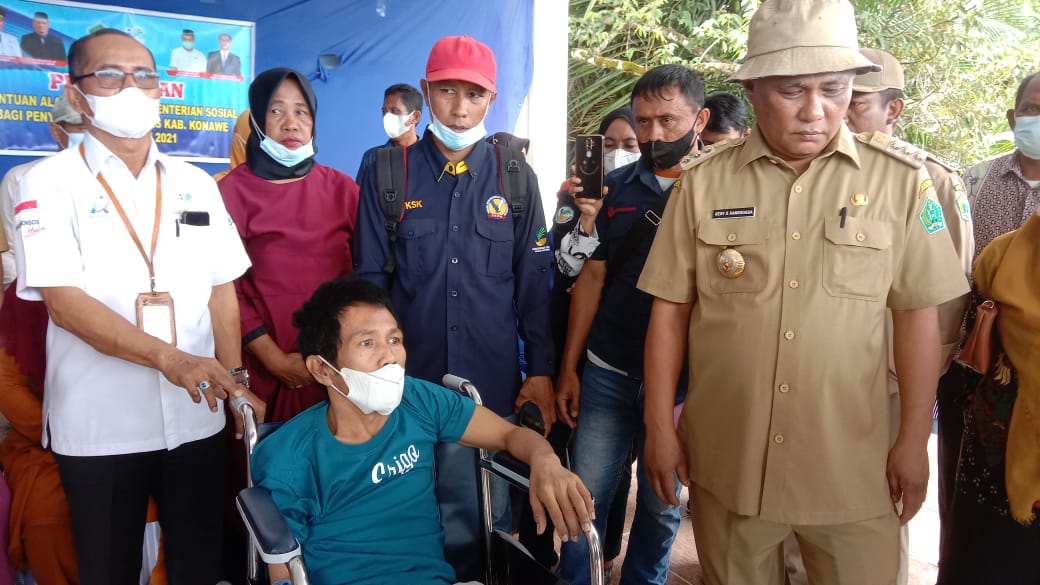 Bupati Konawe, Kery Saiful Konggoasa (kanan) saat menyalurkan kursi roda kepada warga disabilitas. Foto: Ist