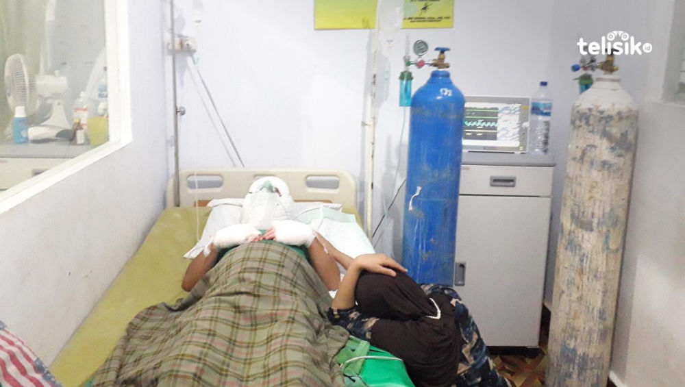 Istri korban, Gunoy menemani suaminya sambil duduk termenung. Korban (Solihin) mengalami luka bakar saat perayaan HUT SMP Negeri 1 Kendari di lapangan SSDC eks MTQ Kota Kendari, Sabtu (2/7/2022). Foto: Aris Mantobua/Telisik