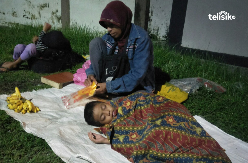 Lia berjualan pisang di pinggir jalan bersama dua orang anaknya yang tertidur. Foto: Thamrin Dalby/Telisik