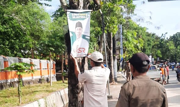 Suasana Satpol PP Kendari saat menertibkan baliho calon Gubernur Sulawesi Tenggara yang terpasang di pohon. Foto: Ist.