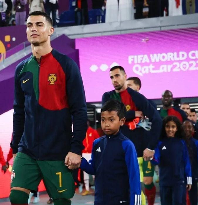 Cristiano Ronaldo menggandeng bocah Indonesia bernama Ulul Albab El Ibrahim dalam laga Portugal vs Ghana di Grup H Piala Dunia 2022. Foto: Repro Instagram