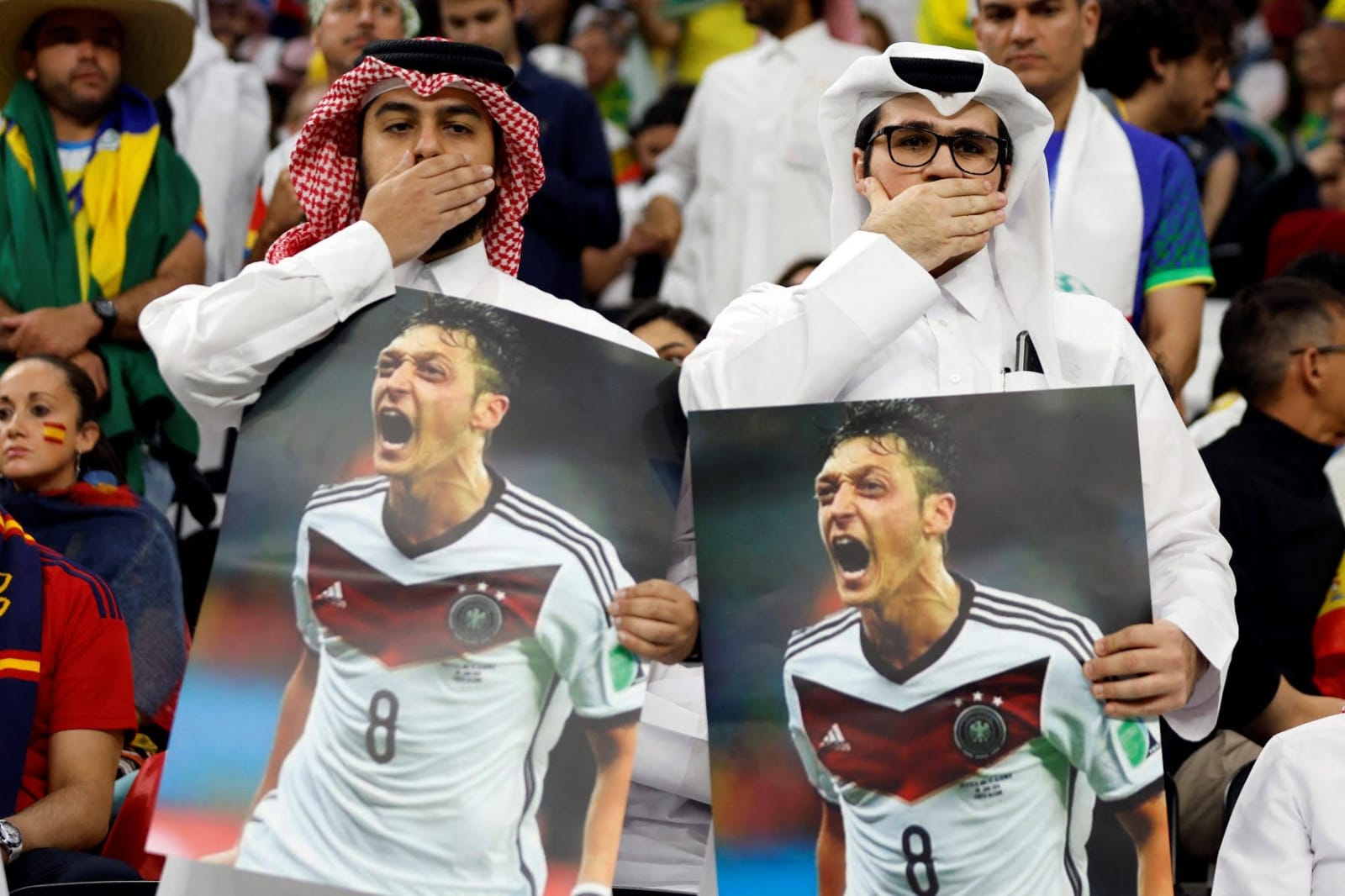 Suporter membawa poster yang menampilkan mantan pemain Jerman Mesut Ozil saat pertandingan Spanyol melawan Jerman pada pertandingan Grup E Piala Dunia 2022 Qatar di Stadion Al Bayt, Al Khor, Qatar. Foto: Repro Reuters