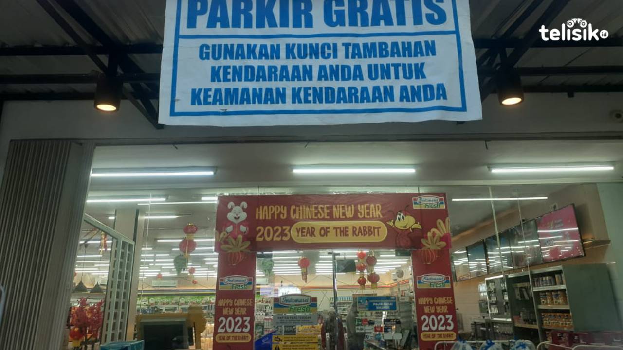 Baliho yang menuliskan parkir gratis di depan Indomaret namun sering diabaikan oleh tukang parkir. Foto: Ahmad Badaruddin/Telisik