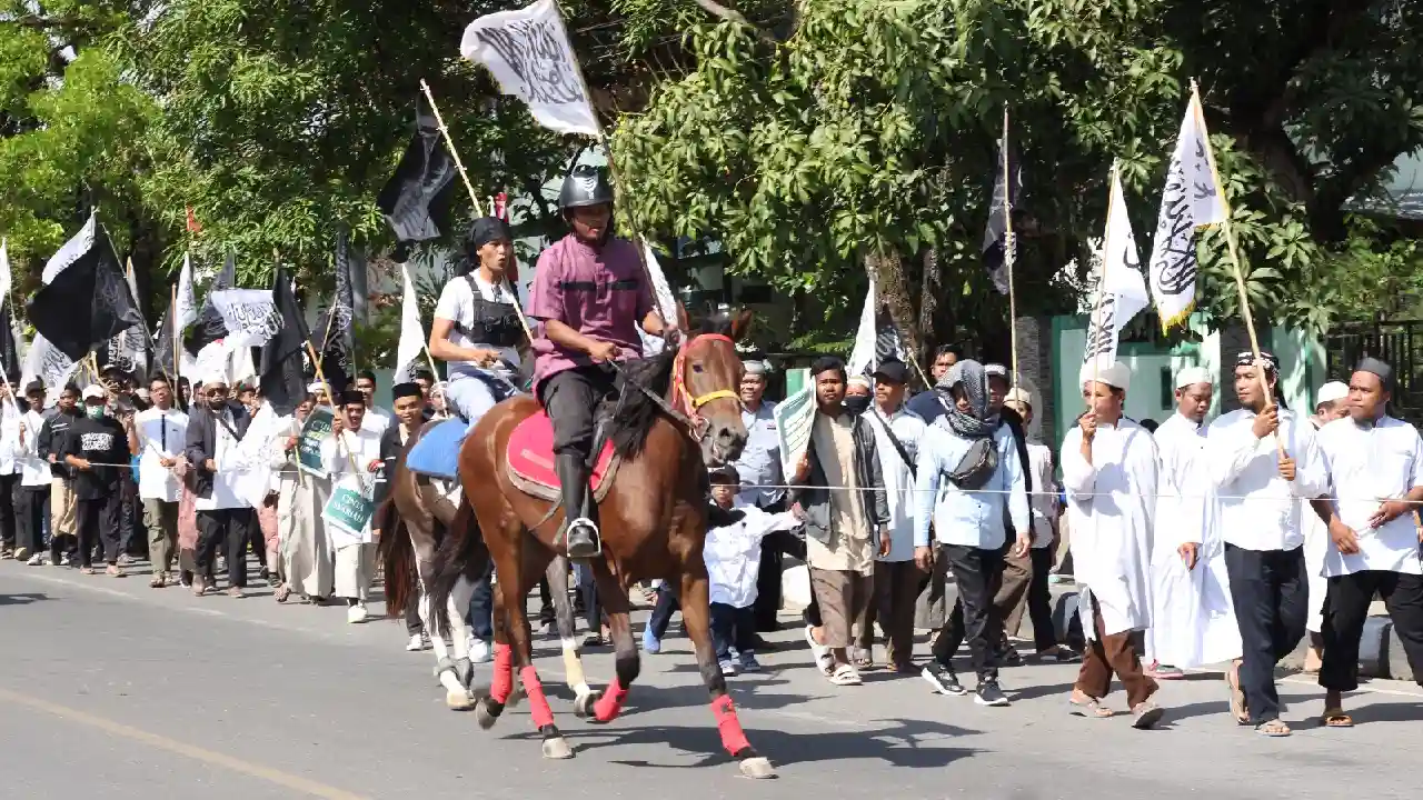 Peserta Pawai Semarak Maulid 1445 H kibarkan bendera tauhid. Foto: Ist.