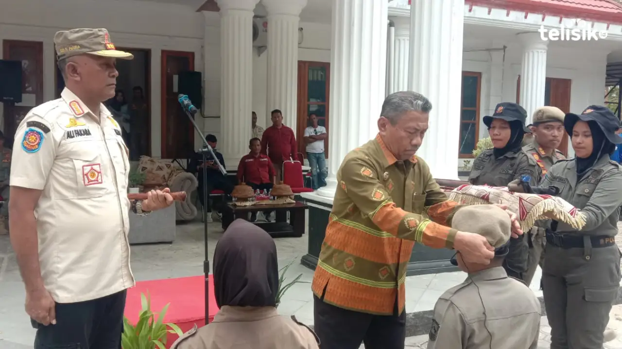 Wabup Muna, Bachrun Labuta memasang baret pada Satpol PP yang baru selesai mengikuti basis. Foto: Sunaryo/Telisik