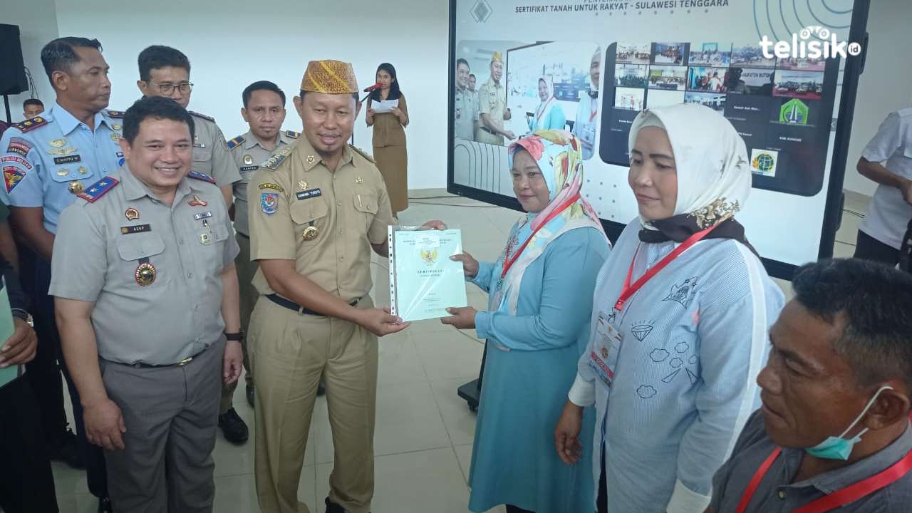 Pj Wali Kota Kendari, Asmawa Tosepu, menyerahkan sertifikat tanah pada perwakilan masyarakat Kota Kendari. Foto: Sumarlin/Telisik