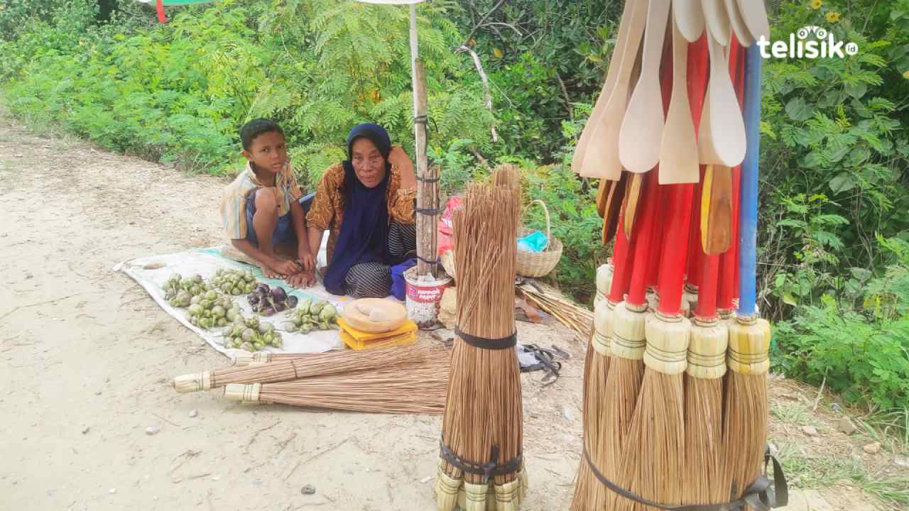 Seorang wanita, Nurhidaya (59) menjual sapu di pinggir jalan bersama cucunya untuk menymbung hidup. Foto: Erni Yanti/Telisik