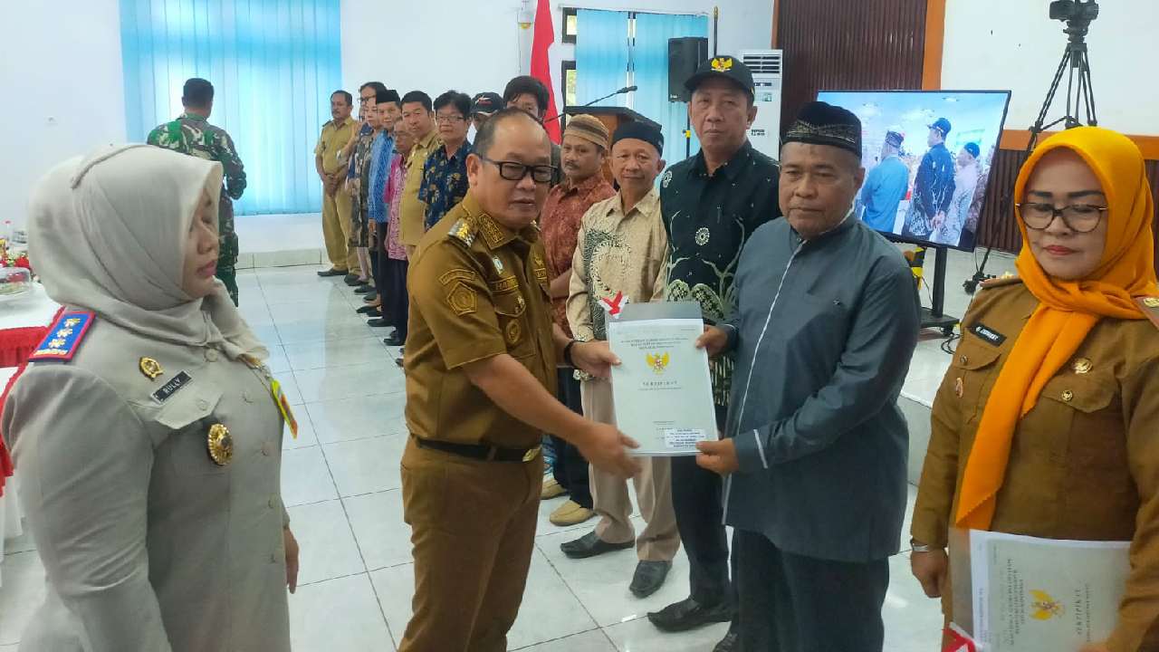 Pj Bupati Konawe saat menyerahkan sertipikat hak atas tanah secara simbolis kepada masyarakat. Foto: Ist.