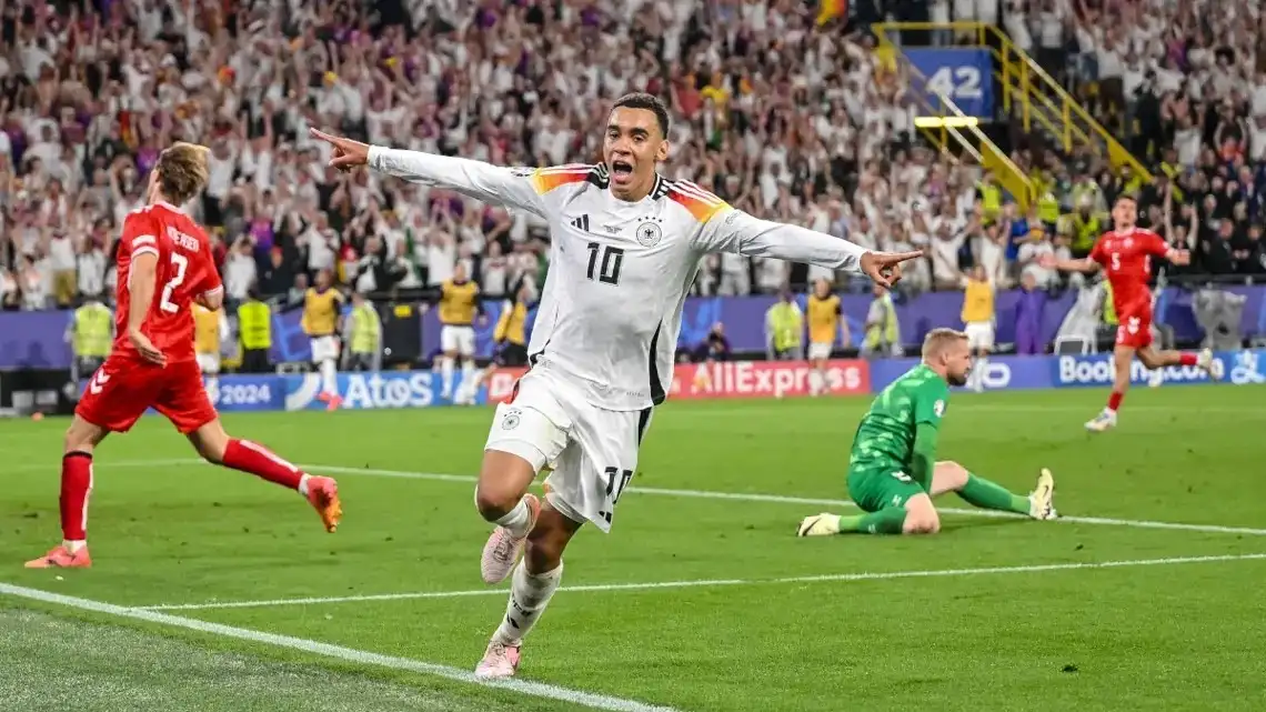 Jamal Musiala melakukan selebrasi usai mencetak gol kedua Jerman ke gawang Denmark pada babak 16 besar Euro 2024 di Stadion BVB, Dortmund, Minggu (30/6/2024) dini hari WIB. Foto: Repro AFP