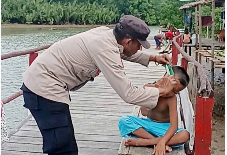 Aiptu Mardianto PM, Kanit Binmas Polsek Lasalimu Polres Buton, saat memberikan layanan cukur gratis kepada masyarakat Dusun Bajo Desa Benteng, kecamatan Lasalimu kabupaten Buton. Foto: Ist.