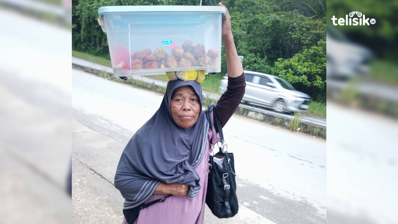 Ibu Nurleni (58) tampak menyusuri jalan raya sambil menjunjung dagangannya. Foto: La Ode Muhammad Adrian Syah/Telisik