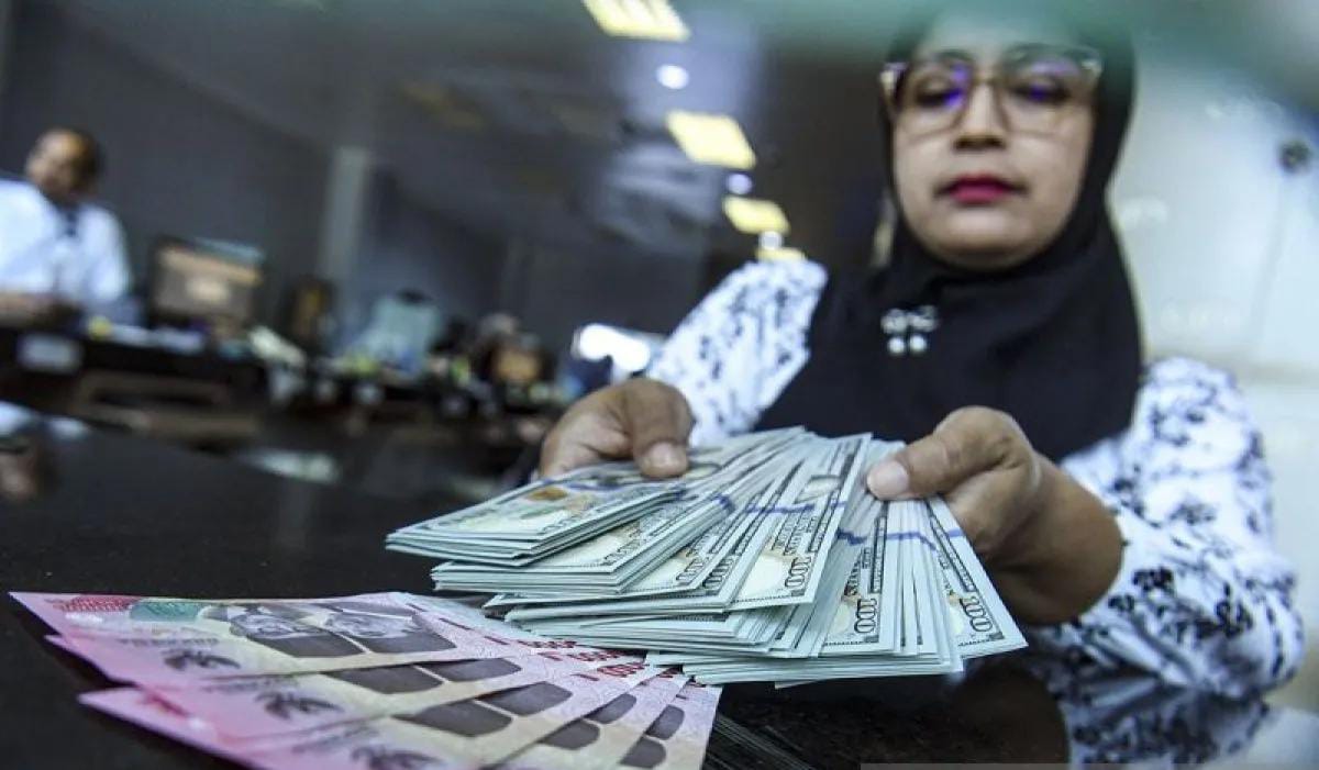 Petugas menjunjukkan uang pecahan dolar AS dan rupiah di gerai penukaran mata uang asing. Foto: Repro Antara