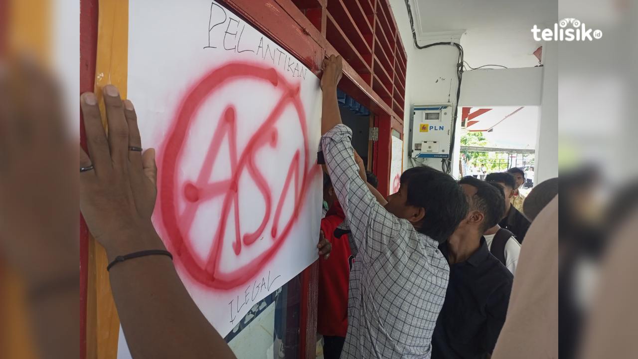 Massa mahasiswa menempel selembaran karton yang bertuliskan pelantikan ASN ilegal di kaca kantor Bupati Buton Selatan, Rabu (26/2/2025). Foto: Ali Iskandar Majid/Telisik