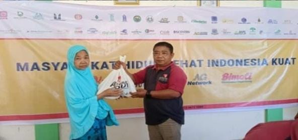 Seorang warga saat menerima paket sembako dari PT Marketindo Selaras, Jumat (21/3/2025). Foto: Ist.