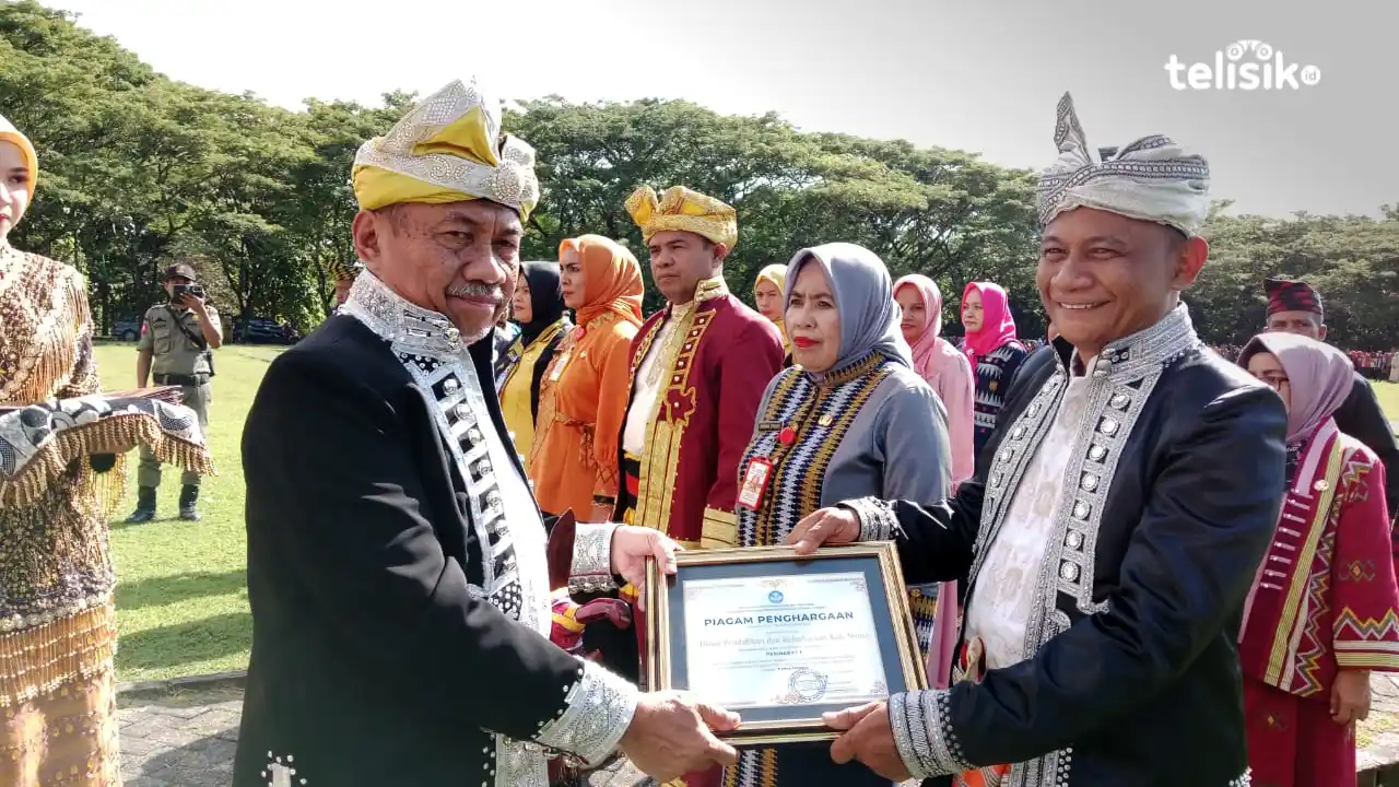Bupati Muna, Bachrun Labuta menyerahkan penghargaan di bidang pendidikan ke Kadikbud, Rahmat Raeba. Foto: Sunaryo/Telisik.