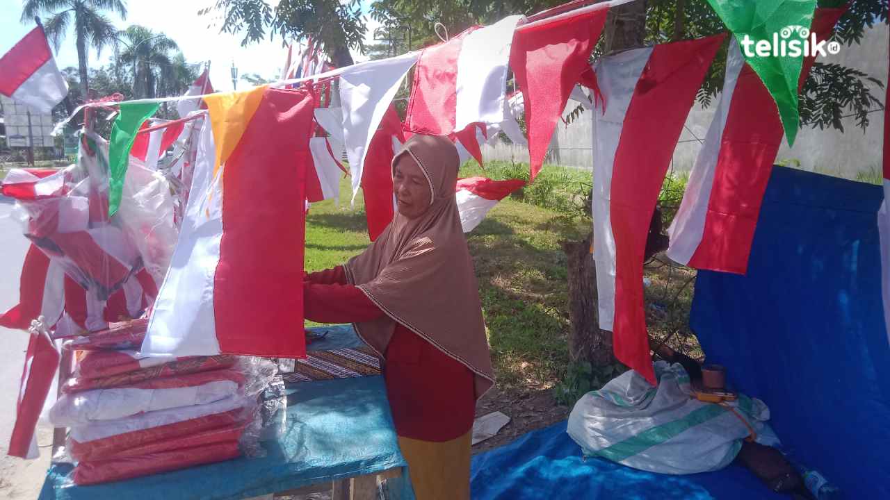 Seorang pedagang pernak-pernik kemerdekaan RI di Kota Kendari, Arafiah (54), sedang merapikan jualannya, Jumat (25/7/2025). Foto: Hamlin/Telisik