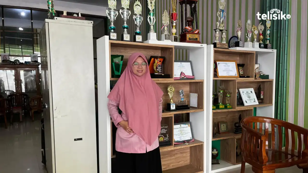 Guru Bidang Kesiswaan Ponpes Ummushabri Kendari, Melisa bersama deretan piala dan piagam penghargaan yang berhasil diraih siswa. Foto: Muh Sapta Perdana/Telisik.