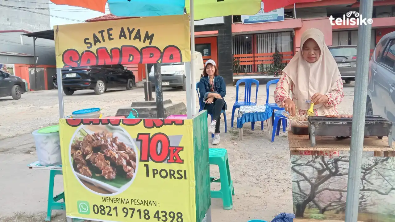 Dewi yang sedang menjaga lapaknya sambil membakar sate untuk dijual. Foto: Niken Ayu Anjani/Telisik.