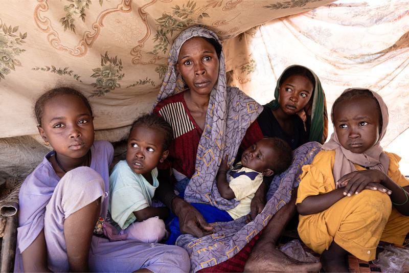 Seorang wanita pengungsi dan sejumlah anak-anak duduk di dalam sebuah tenda yang terbuat dari kayu dan kain di Tawila, Darfur Utara, Sudan. Foto: Program Pangan Dunia PBB/Xinhua