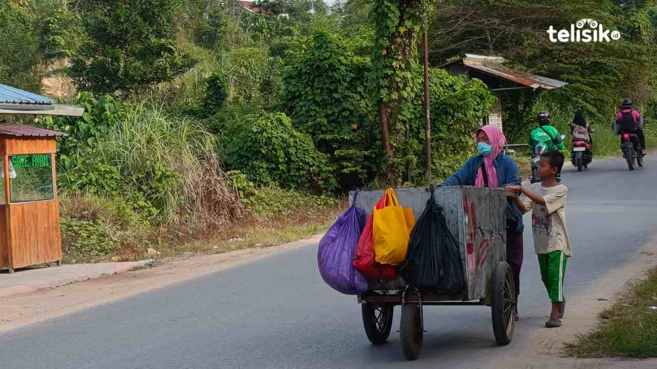Lisna, seorang ibu dengan anaknya nampak mendorong gerobak tua untuk mencari barang bekas. Foto: Gede Suyana Sriski/telisik