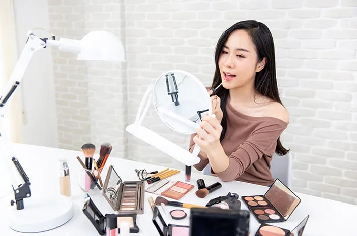 Ilustrasi seorang wanita yang sedang merias wajahnya. Foto: Halodoc.com