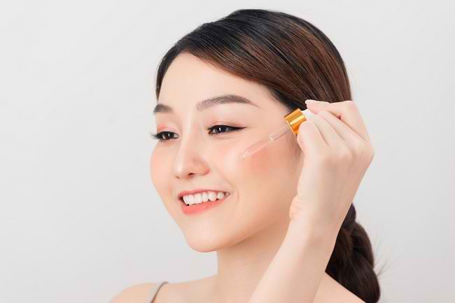 Seorang wanita yang sedang menggunakan serum wajah. Foto: Alodokter