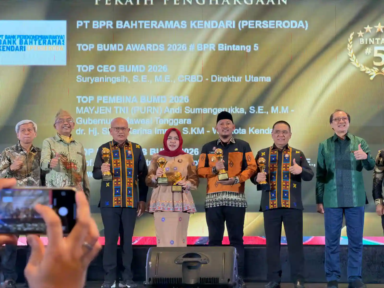 Wakil Wali Kota Kendari Sudirman (tengah, mengenakan peci) , Direktur BPR Bahteramas Kendari Suryaningsih (kiri, berjilbab merah) dan manajemen BPR Bahteramas Kendari berfoto bersama usai menerima penghargaan pada ajang TOP BUMD Awards 2026 di Hotel Raffl