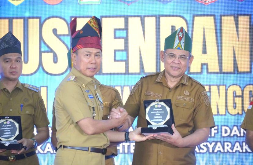 Gubernur Sulawesi Tenggara, Andi Sumangerukka (tengah), saat memberikan penghargaan kepada Wali Kota Baubau, Yusran Fahim. Foto: Ist.