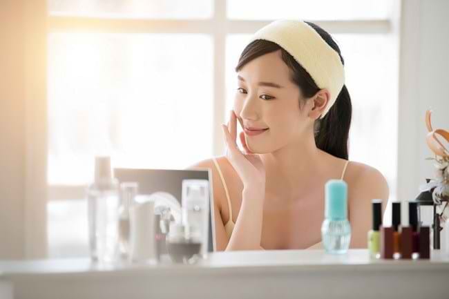 Seorang wanita melakukan perawatan wajah menggunakan rangkaian skincare untuk menjaga kesehatan dan kelembapan kulit. Foto: Alodokter