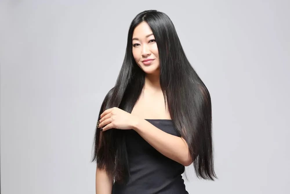 Seorang perempuan memperlihatkan rambut panjang, hitam, dan berkilau yang tampak sehat serta terawat. Foto: Halosehat.